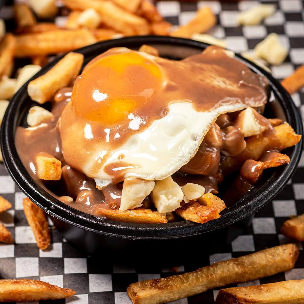 A bowl of food with fries and an egg on top.
