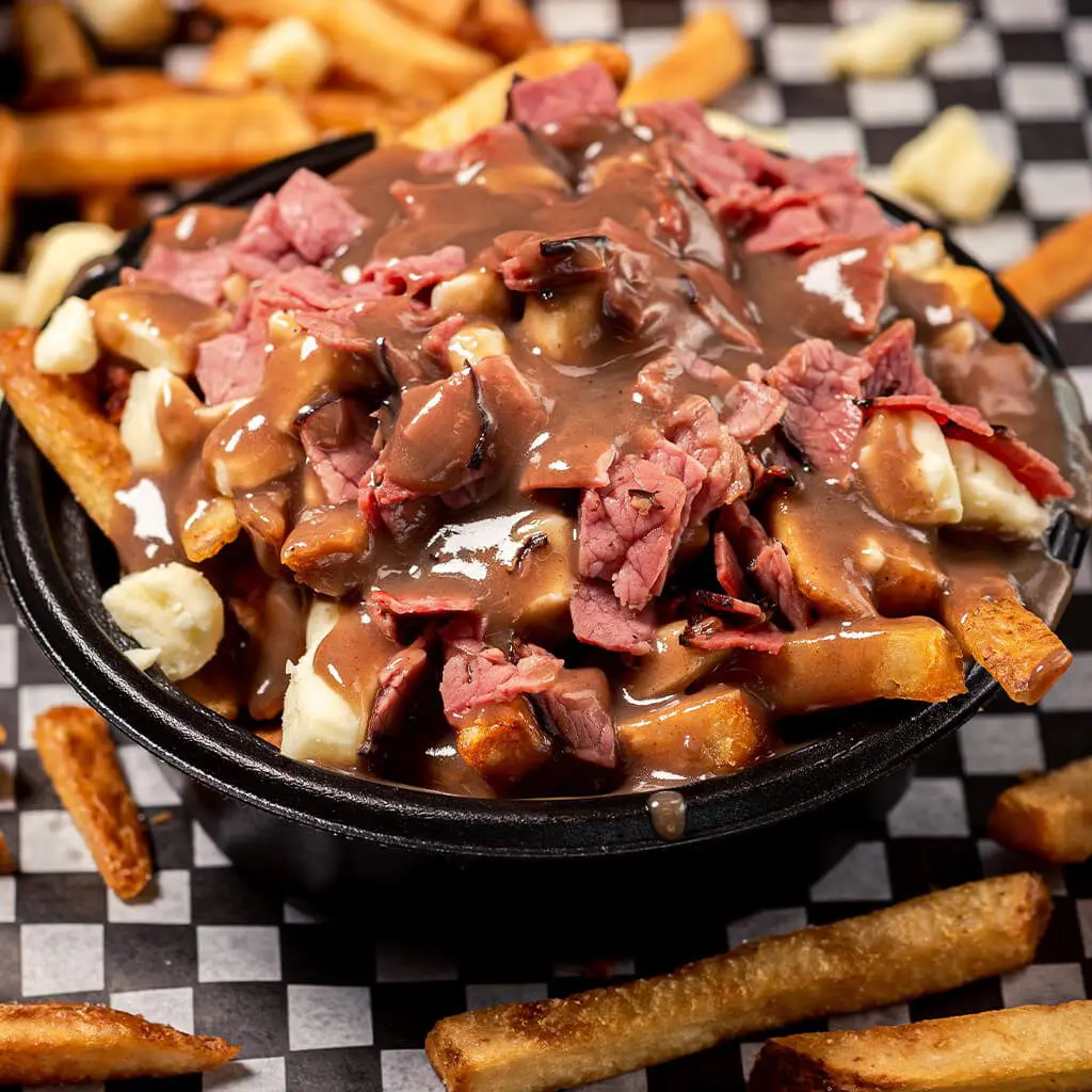 A bowl of fries covered in gravy and meat.