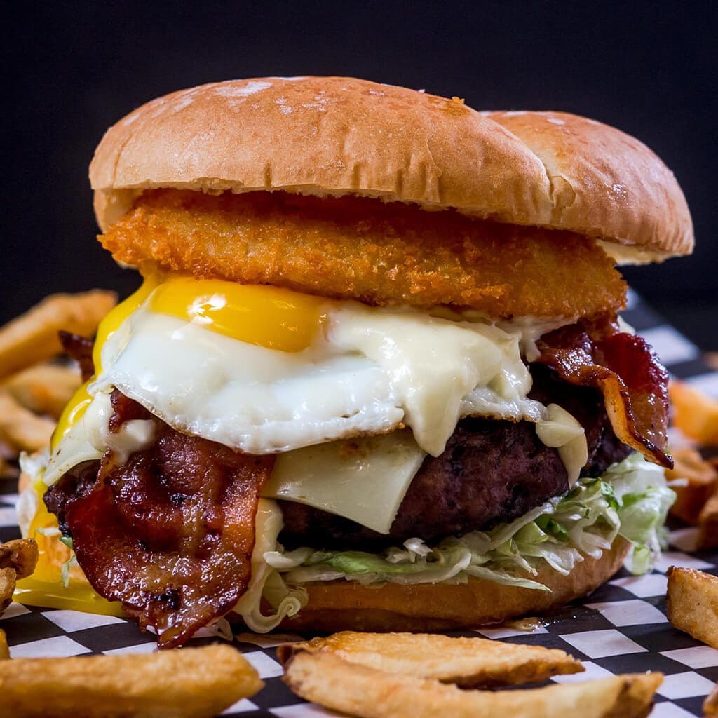 A burger with bacon, egg and cheese on top of a bun.